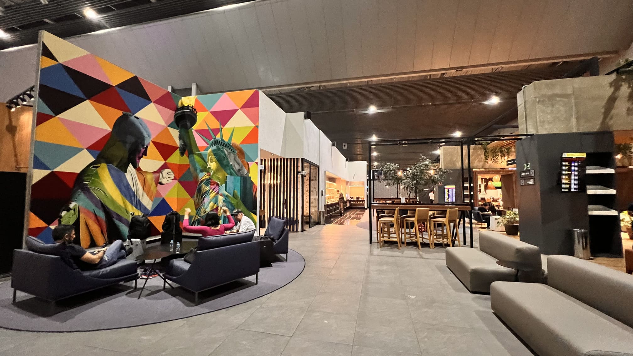 Sala VIP Centurion Lounge da American Express Aeroporto de Guarulhos. Este lounge é espaçoso e apresenta um design tradicional. Oferece um buffet com diversas opções quentes e frias, um bar, área dedicada à leitura e trabalho, instalações para conferência e sala de silêncio